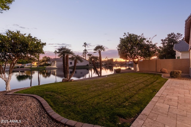 yard at dusk featuring a water view