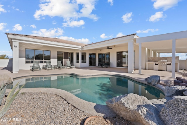 view of swimming pool with ceiling fan, a patio area, and an outdoor kitchen