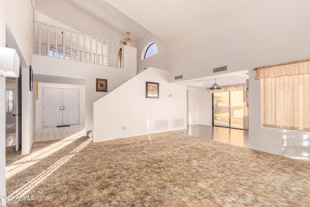 unfurnished living room with carpet floors and high vaulted ceiling