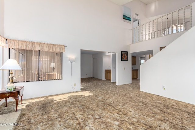 unfurnished living room featuring carpet floors and a high ceiling