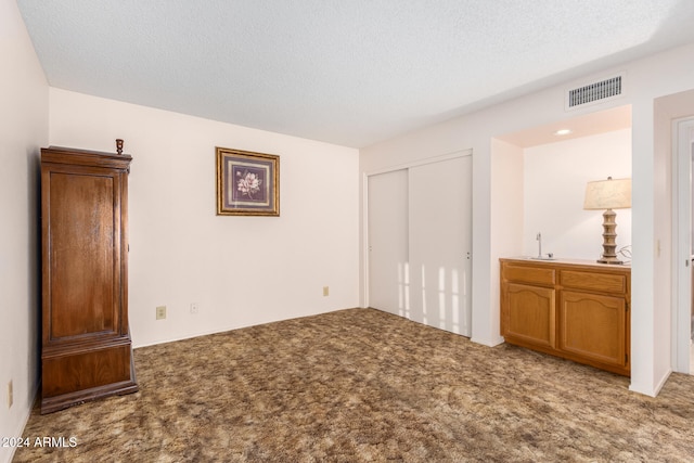 unfurnished bedroom with light colored carpet and a textured ceiling