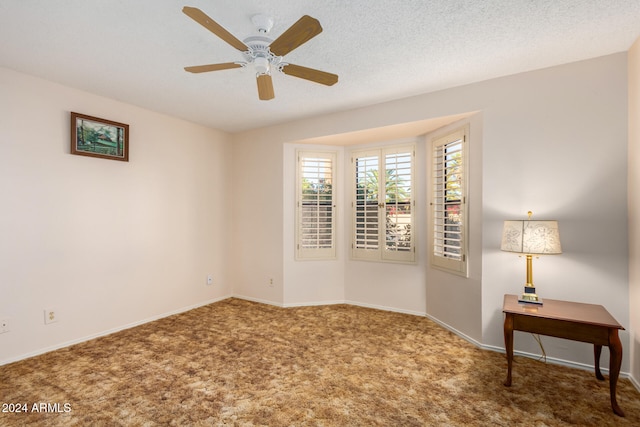 carpeted spare room with ceiling fan and a textured ceiling