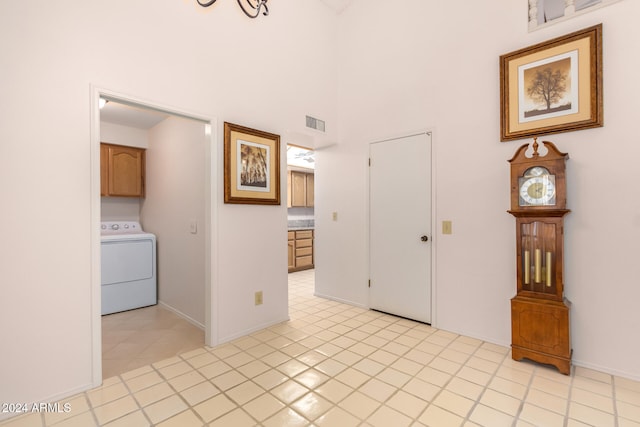 interior space featuring a towering ceiling, light tile patterned flooring, and washer / dryer