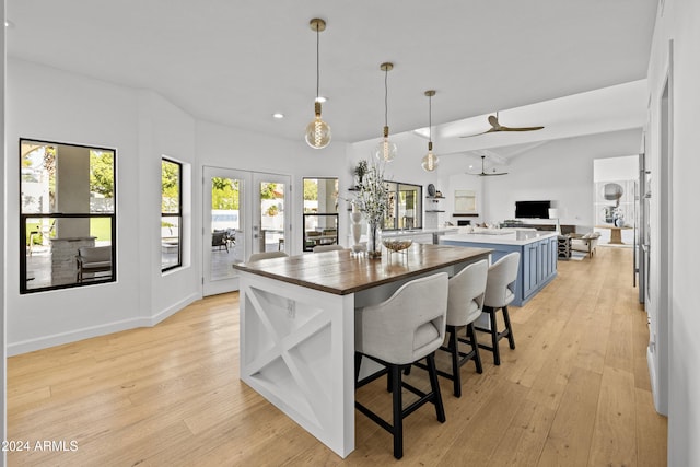 kitchen featuring light hardwood / wood-style floors, decorative light fixtures, ceiling fan, and a breakfast bar