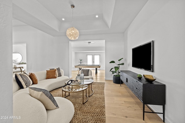 living room with a tray ceiling and light hardwood / wood-style flooring