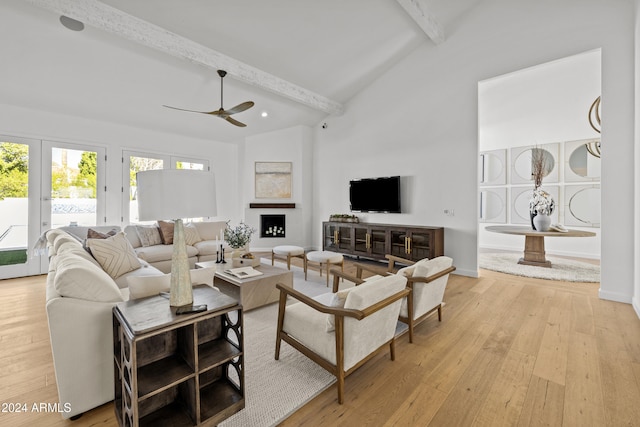 living room featuring high vaulted ceiling, light hardwood / wood-style floors, beamed ceiling, and ceiling fan