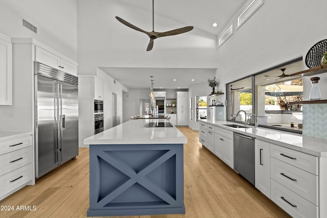 kitchen featuring light hardwood / wood-style floors, white cabinetry, sink, appliances with stainless steel finishes, and a center island