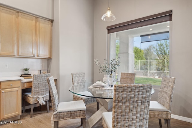 dining room featuring baseboards, light wood-style flooring, and built in desk