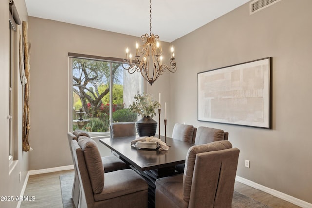 dining space with visible vents, baseboards, wood finished floors, and a chandelier