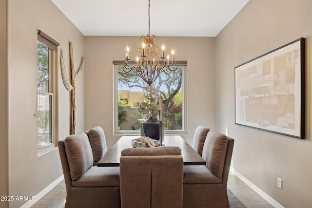 dining space featuring baseboards, a notable chandelier, and wood finished floors