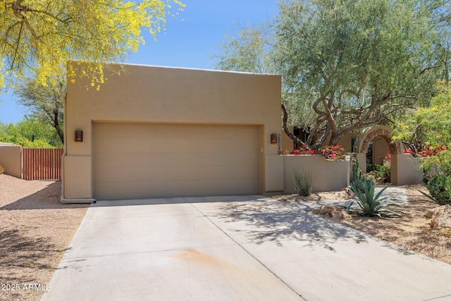 view of front of property featuring driveway, a gate, fence, an attached garage, and stucco siding
