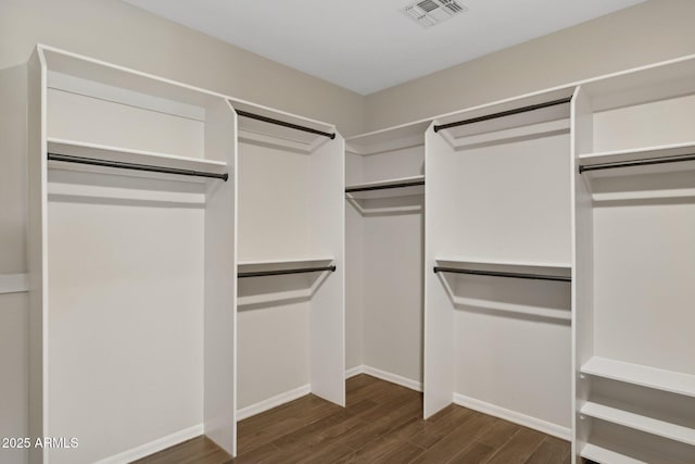 walk in closet with visible vents and dark wood finished floors