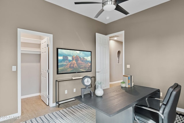 office featuring baseboards, a ceiling fan, wood finished floors, and visible vents