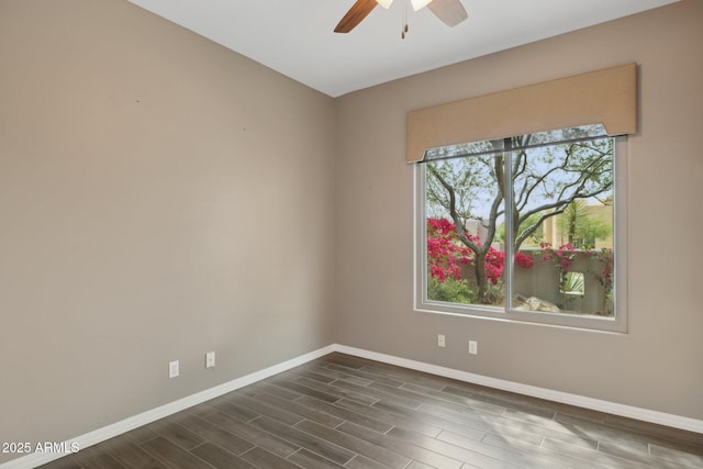 spare room with ceiling fan, baseboards, and dark wood-type flooring