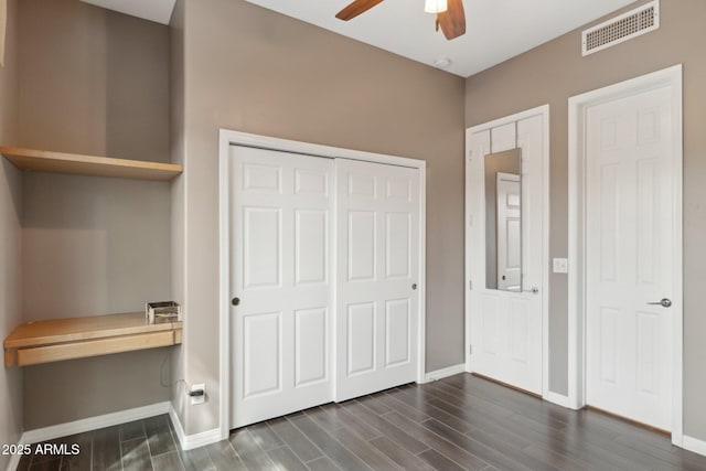 unfurnished bedroom featuring visible vents, a closet, dark wood-style flooring, baseboards, and a ceiling fan
