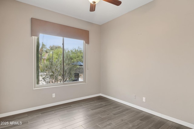 spare room with baseboards, ceiling fan, and dark wood-type flooring