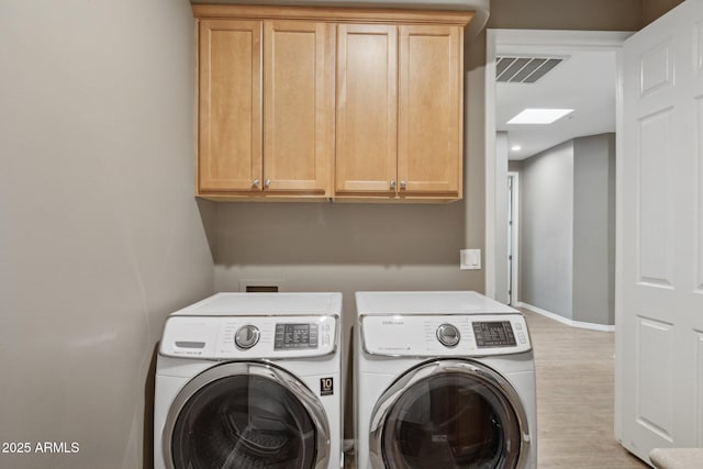 clothes washing area featuring visible vents, light wood finished floors, cabinet space, and washer and dryer