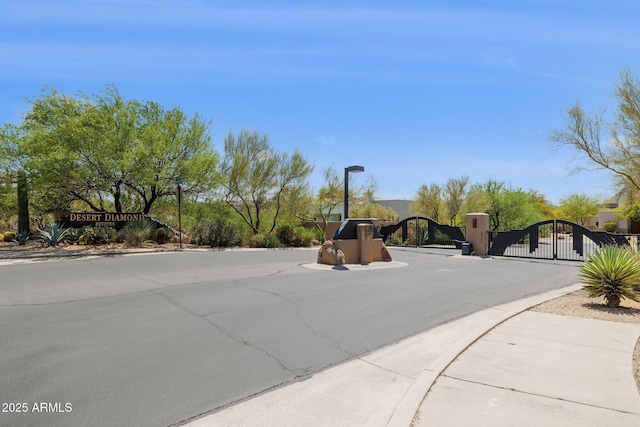 view of street featuring a gate, a gated entry, curbs, and sidewalks