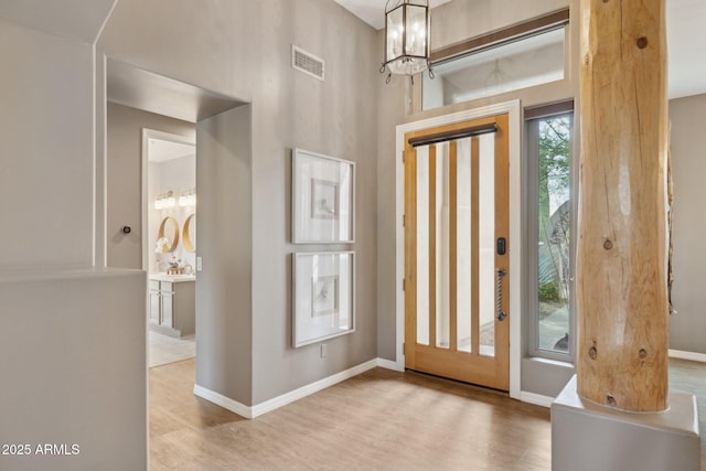 entrance foyer with baseboards, visible vents, wood finished floors, and a chandelier