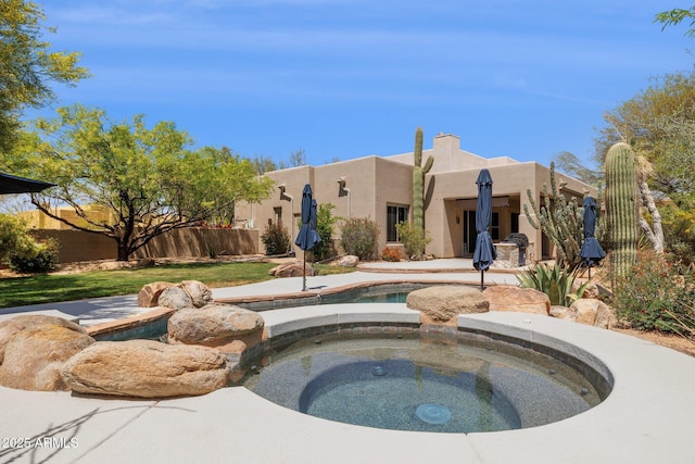 view of swimming pool with fence, a fenced in pool, and an in ground hot tub
