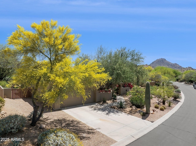 surrounding community with a garage, fence, a mountain view, and driveway