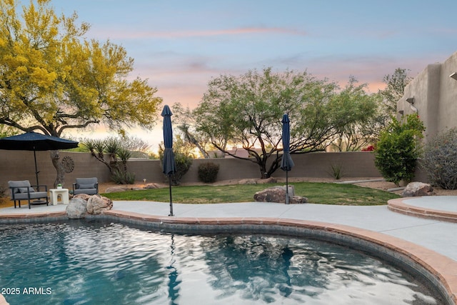pool at dusk with a fenced backyard, a fenced in pool, and a patio