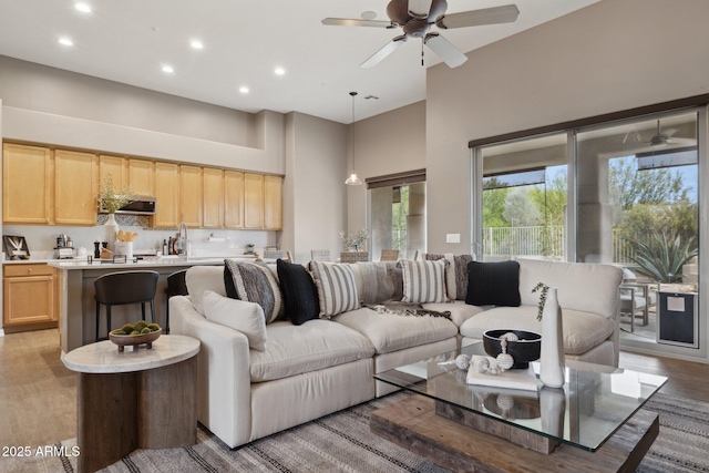 living area with recessed lighting, a towering ceiling, and ceiling fan