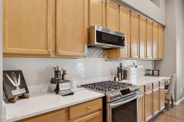 kitchen with light countertops, appliances with stainless steel finishes, tasteful backsplash, and light brown cabinets