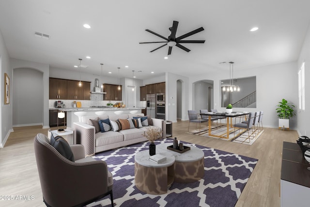 living room featuring ceiling fan with notable chandelier and light hardwood / wood-style floors