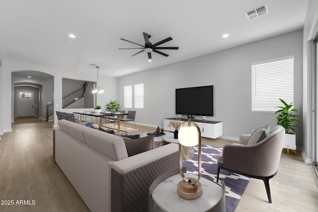 living room featuring light hardwood / wood-style floors and ceiling fan with notable chandelier