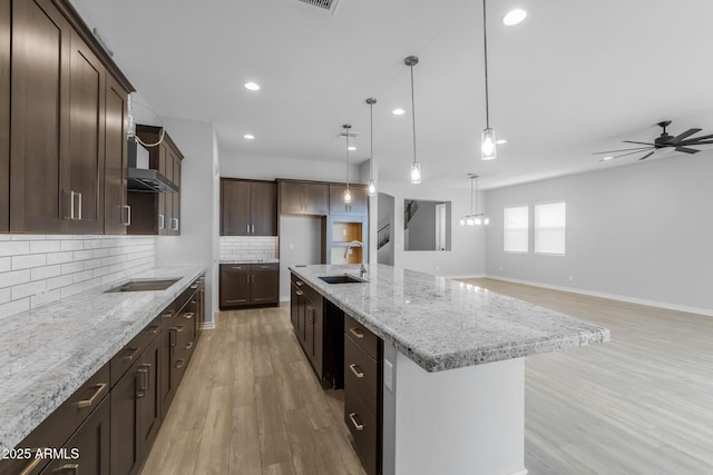 kitchen with ceiling fan, decorative light fixtures, sink, an island with sink, and black electric cooktop