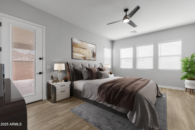 bedroom featuring ceiling fan, access to exterior, light hardwood / wood-style flooring, and multiple windows