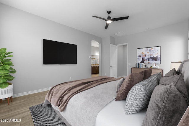 bedroom with ceiling fan, connected bathroom, and light hardwood / wood-style flooring