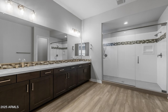 bathroom featuring a shower with shower door, vanity, backsplash, and wood-type flooring