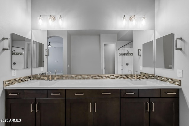 bathroom with ceiling fan, vanity, decorative backsplash, and a shower with door