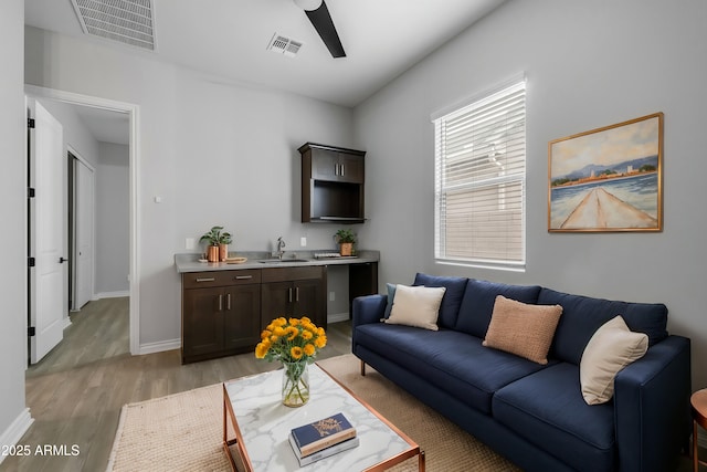 living room featuring ceiling fan, sink, and light hardwood / wood-style floors