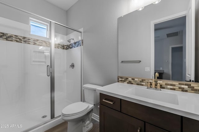 bathroom featuring toilet, tasteful backsplash, an enclosed shower, and vanity