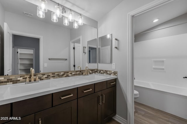 bathroom with backsplash, toilet, vanity, and hardwood / wood-style floors