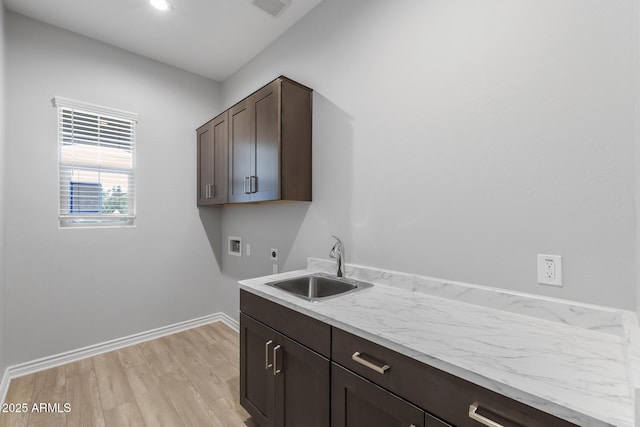 washroom featuring light hardwood / wood-style floors, sink, hookup for a washing machine, electric dryer hookup, and cabinets