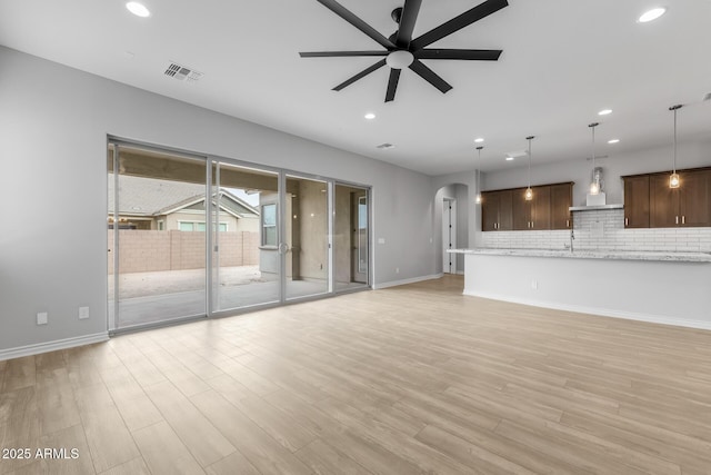 unfurnished living room featuring ceiling fan, light hardwood / wood-style flooring, and sink