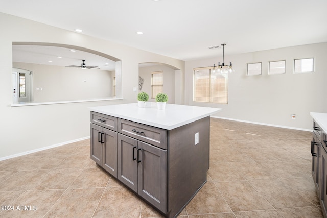 kitchen with a kitchen island, light tile flooring, decorative light fixtures, and ceiling fan with notable chandelier