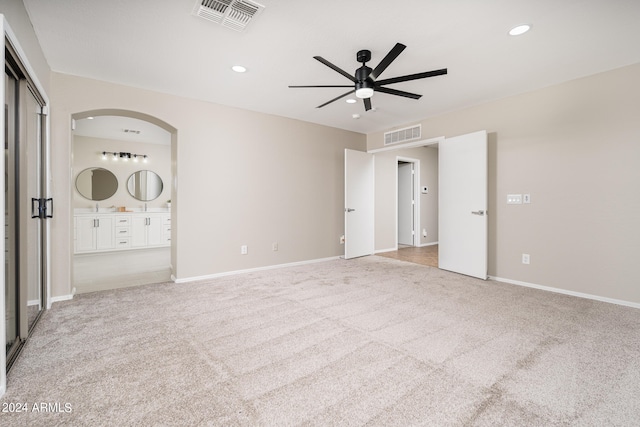 unfurnished bedroom with light carpet, ceiling fan, and ensuite bathroom