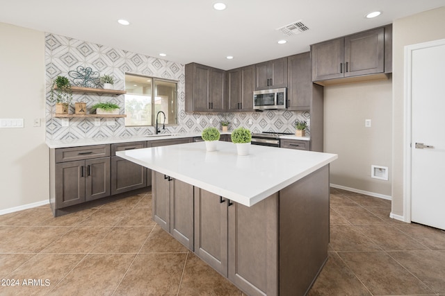 kitchen featuring appliances with stainless steel finishes, dark brown cabinetry, tasteful backsplash, a kitchen island, and tile flooring