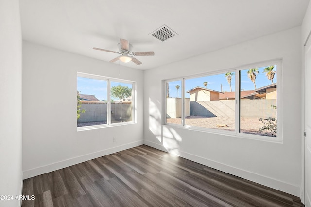 empty room featuring visible vents, baseboards, ceiling fan, and dark wood-style flooring