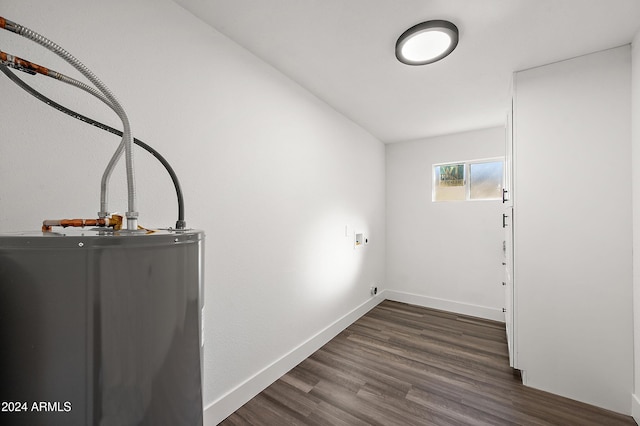 clothes washing area featuring dark wood-style flooring, hookup for a washing machine, water heater, laundry area, and baseboards