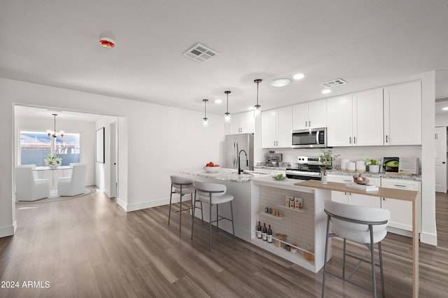 kitchen with appliances with stainless steel finishes, a breakfast bar area, dark wood finished floors, and visible vents