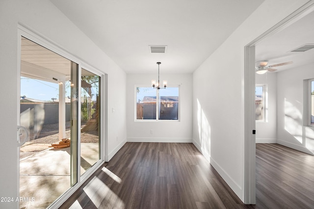 unfurnished dining area featuring baseboards, visible vents, dark wood finished floors, and ceiling fan with notable chandelier