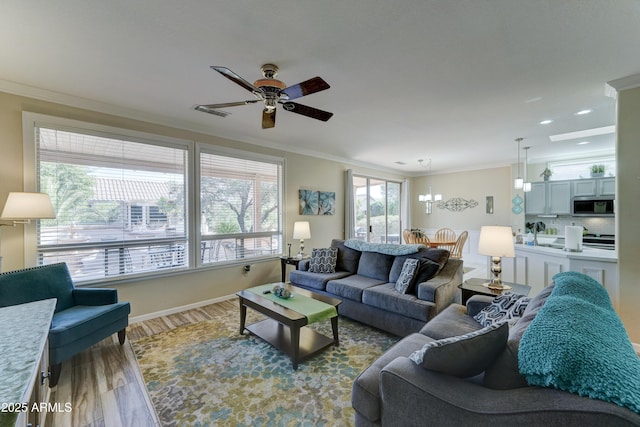 living room with hardwood / wood-style flooring, ornamental molding, and ceiling fan