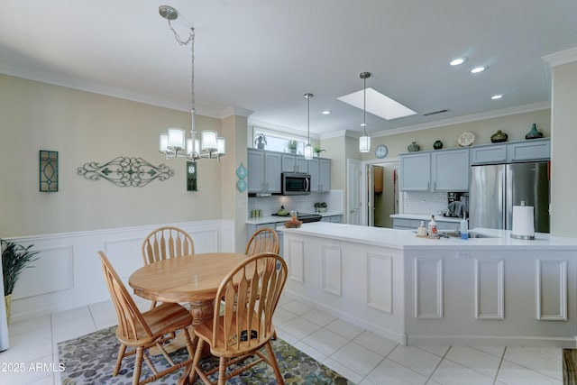 dining area with light tile patterned floors, crown molding, and a skylight