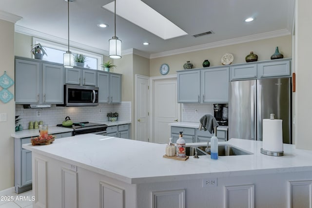 kitchen with stainless steel appliances, hanging light fixtures, a center island with sink, and light stone counters